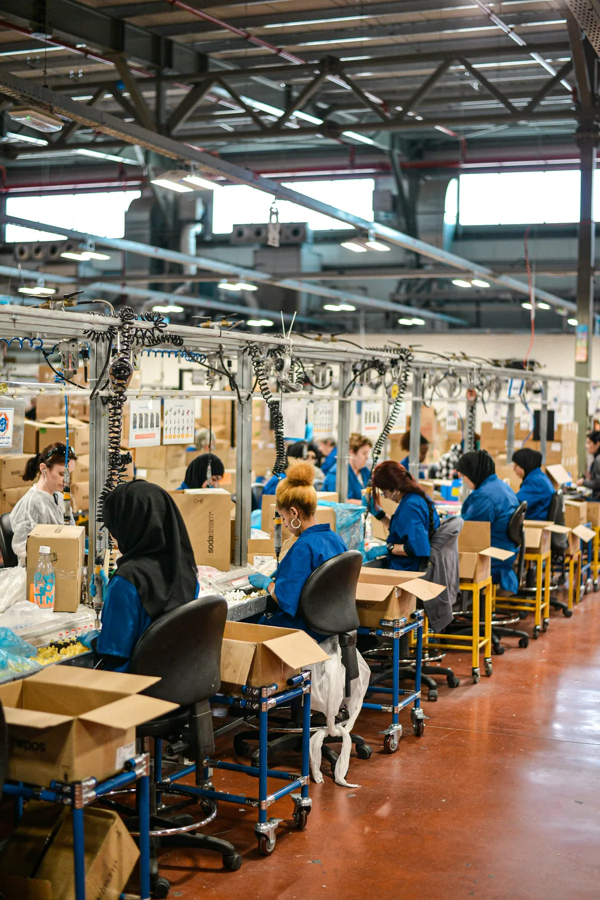 Employés en uniforme bleu au travail sur une chaîne d'assemblage dans une grande usine