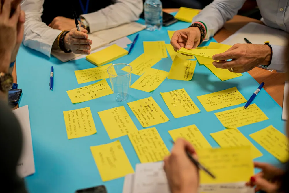 Vue de dessus : des mains placent des papillons adhésifs jaunes sur une table pendant un atelier