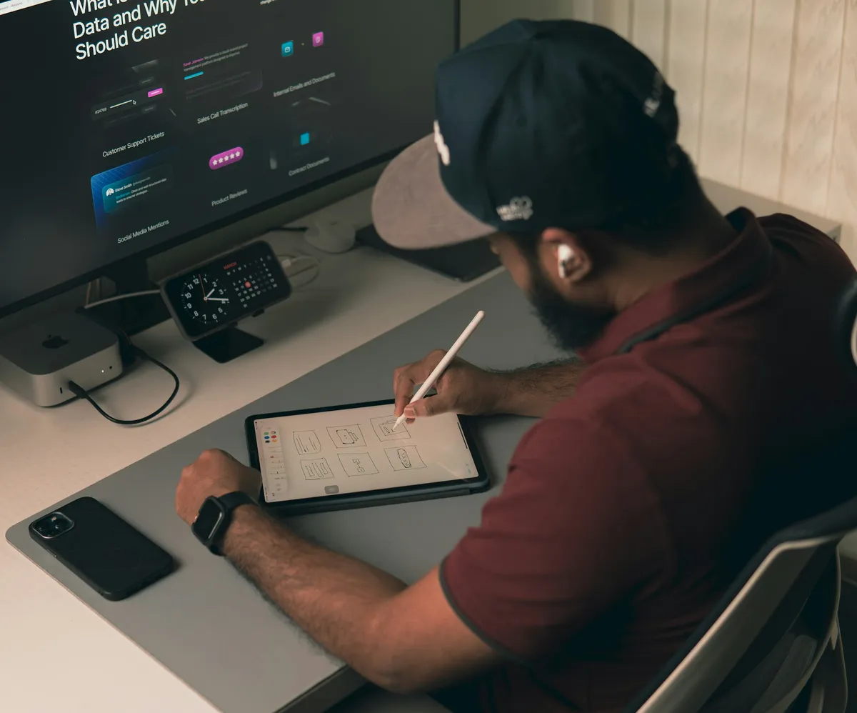 Jeune créateur qui dessine une interface sur sa tablette, devant un écran affichant le design d'une application